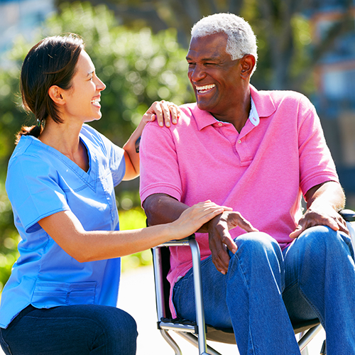 Carer Pushing Senior Man In Wheelchair